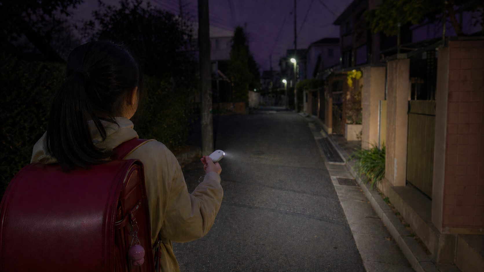 SwitchBot防犯ブザーのLEDライトで足元を照らしながら夜道を歩く子供の後ろ姿